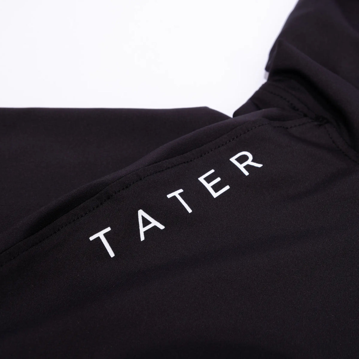 &quot;Detail of a black short-sleeve baseball hoodie with the &#39;TATER&#39; logo printed in white, part of the Tater Baseball FUNDAMENTALS collection.