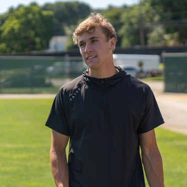 Athlete Korey Morton wearing a black tactical quarter-zip baseball hoodie with the 'TATER' logo, ready for active outdoor training.