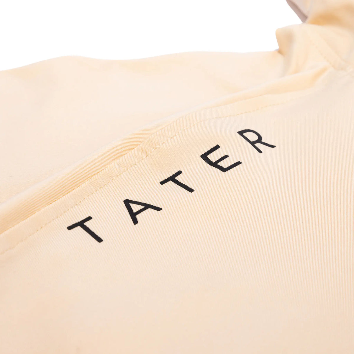 Close-up of a tan hoodie with the &#39;TATER&#39; brand logo in bold black letters along the hood&#39;s edge, showcasing the brand&#39;s strong identity.