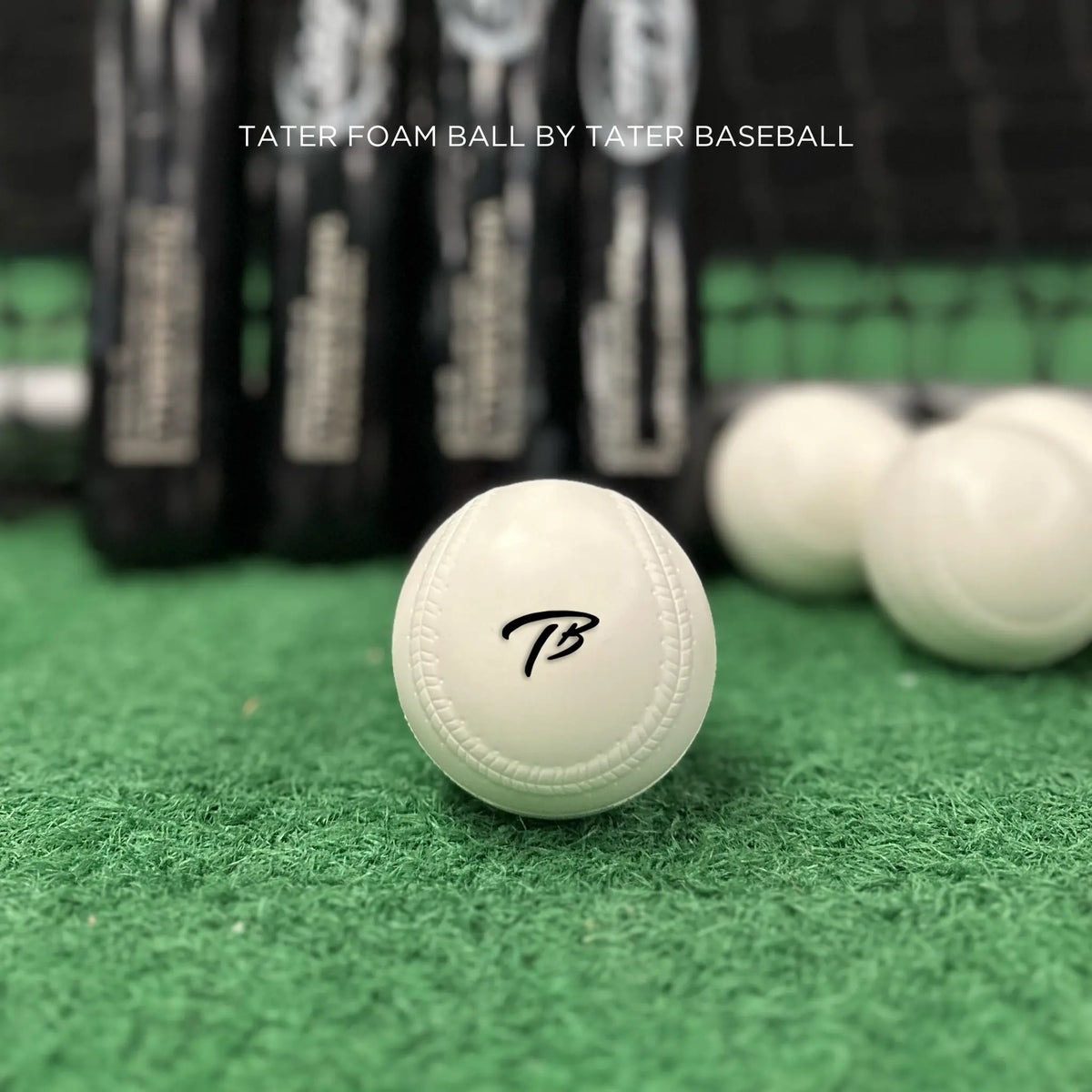 White foam baseball with TB resting on turf with training bats in the background