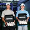 Two players holding open boxes of Tater foam pitching machine balls, two dozen per box, in an indoor batting cage