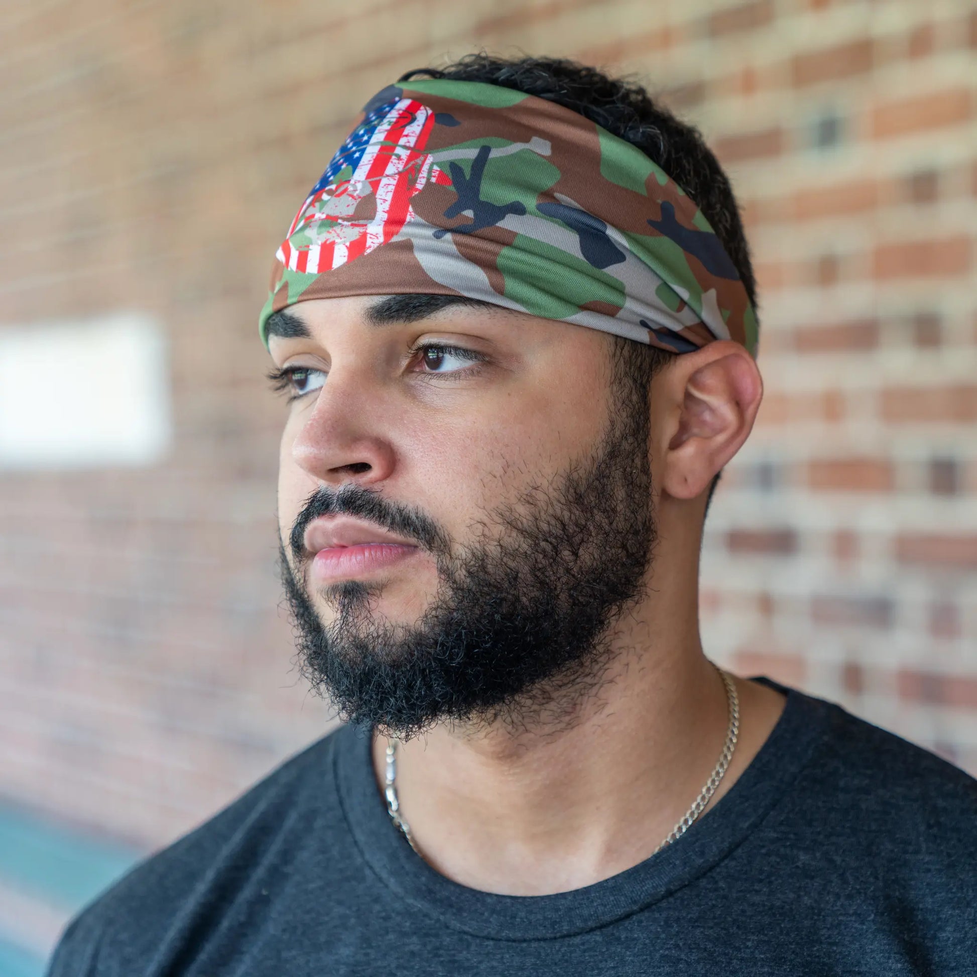 Profile view of a contemplative baseball player sporting a Tater Baseball camo headband featuring the USA flag, reflecting a commitment to both sport and country.
