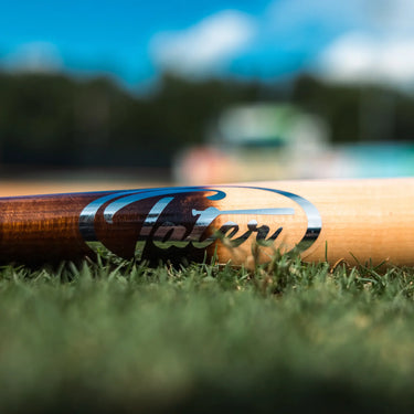 Close-up of the Tater logo on an X12 Pro maple bat resting on grass